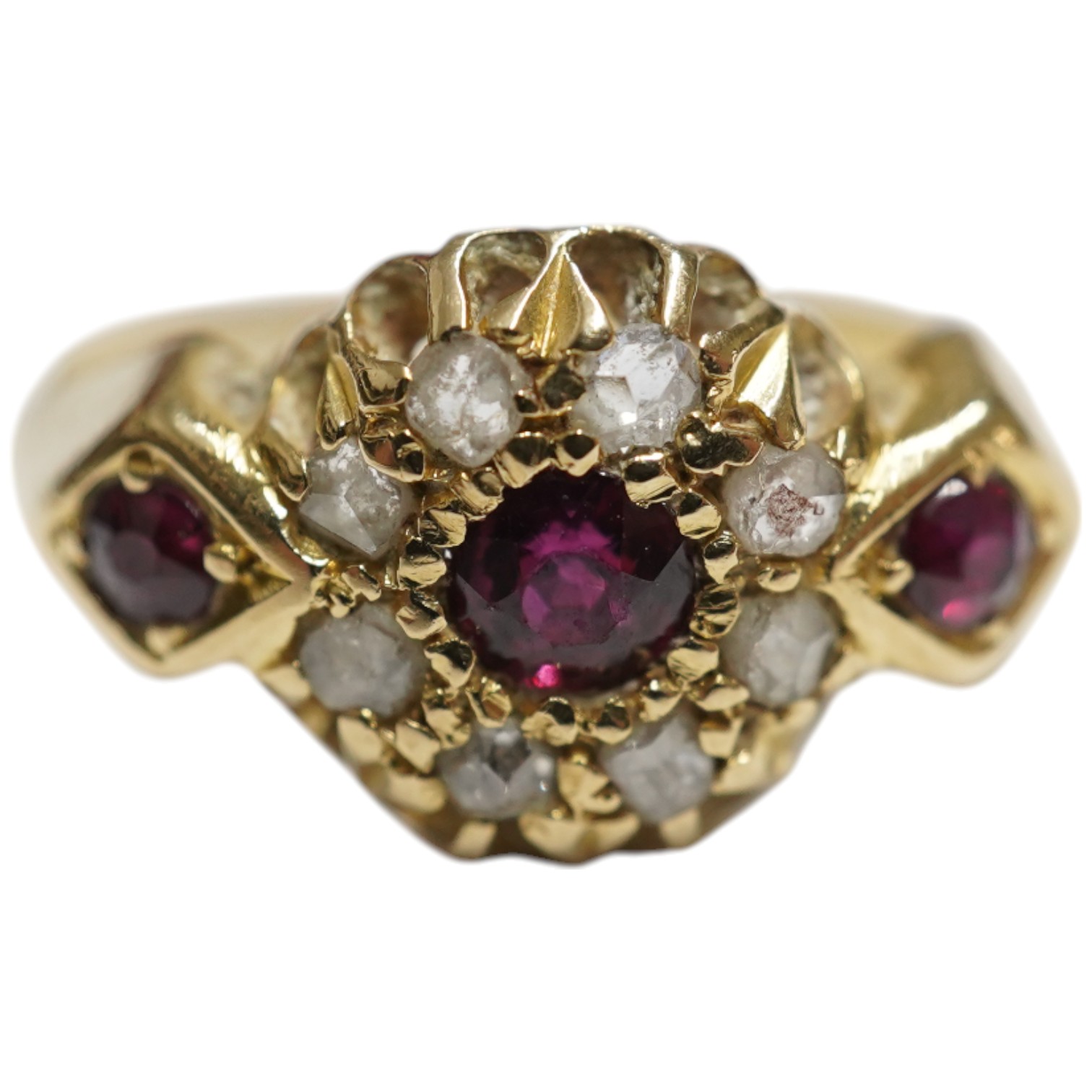 An early 20th century yellow metal and three stone ruby set ring, the centre stone bordered with rose cut diamonds, size H/I, gross weight 2.8 grams.
